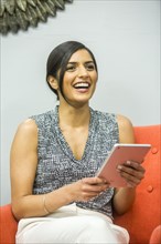 Laughing Asian woman using digital tablet