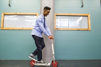 Black man riding scooter indoors