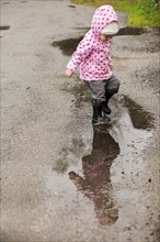 Caucasian girl wearing boots splashing in puddle