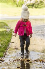 Caucasian girl wearing boots splashing in puddle