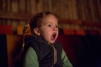 Surprised Caucasian girl watching movie in theater