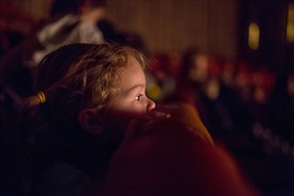 Caucasian girl leaning on chair watching movie in theater