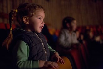Girl leaning on chair watching movie in theater