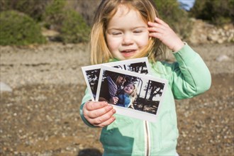 Caucasian girl showing photograph of her with mother
