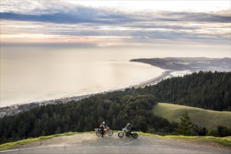 People on motorcycles at edge of cliff near ocean