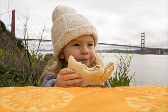 Caucasian girl eating sandwich outdoors