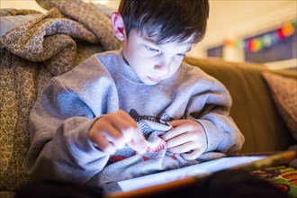 Mixed Race boy using digital tablet at night