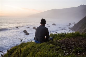 Caucasian man admiring ocean waves at sunset