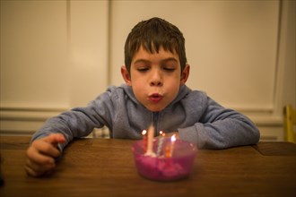 Mixed Race boy blowing candles on table