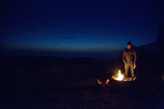 Caucasian man watching campfire at night