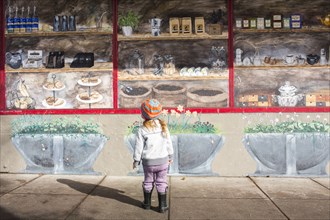 Caucasian girl standing on sidewalk admiring mural on wall