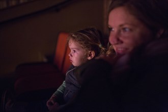Caucasian mother and daughter watching movie in theater