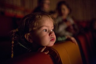 Caucasian girl watching movie in theater