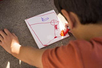 Mixed Race boy drawing on paper with marker