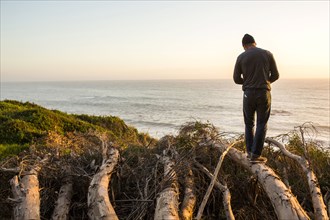 Caucasian man balancing on logs admiring scenic view of ocean