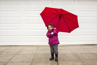 Caucasian girl holding red umbrella in wind