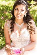 Smiling Hispanic girl wearing gown holding flower