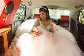 Smiling Hispanic girl texting on cell phone in limousine