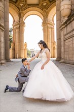 Hispanic boy wearing suit kissing hand of girl wearing gown