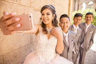 Hispanic girl and boys posing for cell phone selfie