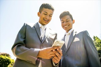 Hispanic boys wearing suits texting on cell phone