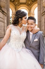 Hispanic girl wearing gown kissing boy on forehead