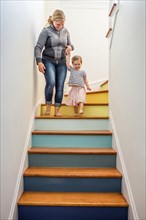 Caucasian mother and daughter descending multicolor staircase
