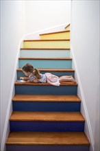 Caucasian girl using digital tablet on multicolor staircase