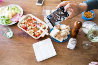 Woman photographing appetizers on table with cell phone