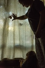 Caucasian mother and daughter looking at window curtain