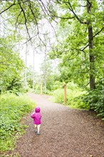 Caucasian girl walking on path in forest