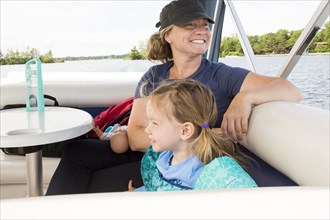 Smiling Caucasian mother and daughter relaxing on boat