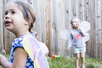 Curious girls wearing fairy wings in backyard