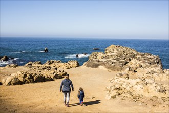 Caucasian mother and daughter walking near ocean