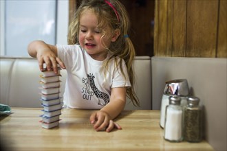 Smiling Caucasian girl stacking jelly containers in restaurant booth