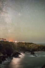 Night sky over cliff at ocean