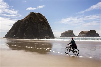Caucasian woman riding bicycle on beach