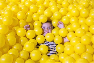 Caucasian girl laying in pile of yellow balls