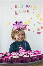Caucasian girl holding tray of cupcakes for birthday