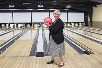 Portrait of Caucasian woman holding bowling ball near lane