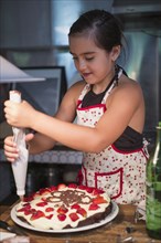 Caucasian girl decorating cake in kitchen