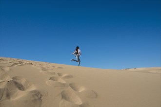Caucasian woman running on sand dune