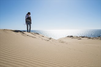 Caucasian woman standing on sand dune near ocean