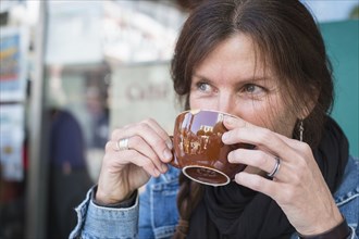 Caucasian woman drinking cup of coffee outdoors
