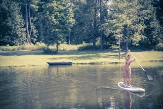 Caucasian woman paddleboarding in lake