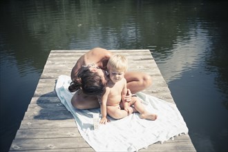 Caucasian mother kissing son on wooden dock in lake