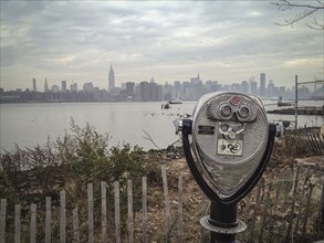 Coin-operated binoculars viewing city skyline on urban waterfront