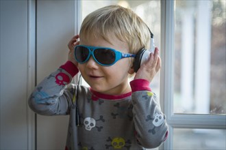 Caucasian boy wearing headphones and sunglasses indoors