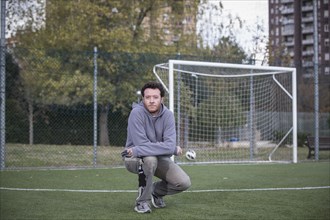 Caucasian man crouching on soccer field in urban park