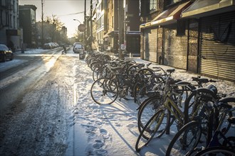 Bicycles parked in snow on city sidewalk